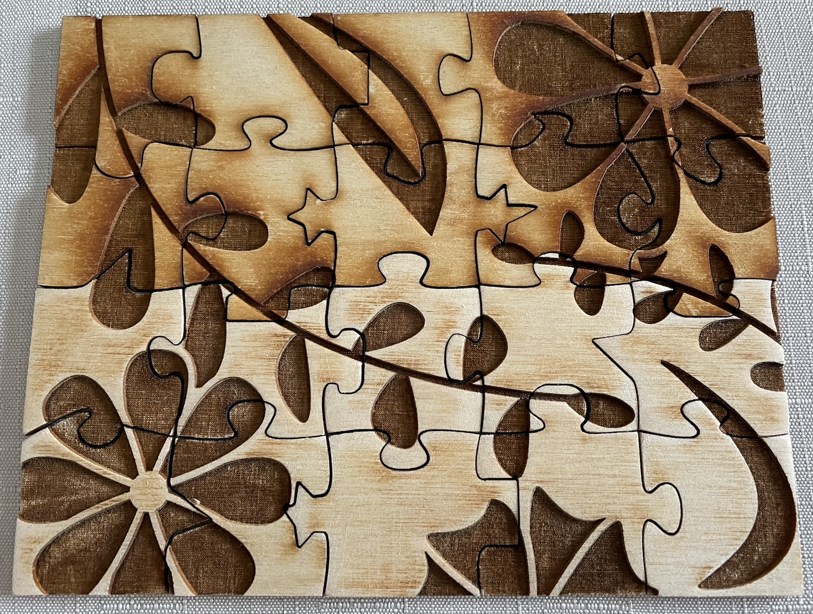 20 piece puzzle, with the bottom 10 piece sanded and the top 10 pieces unsanded. The sanded pieces are whiter, while the unsanded pieces have a variety of brown burn marks.