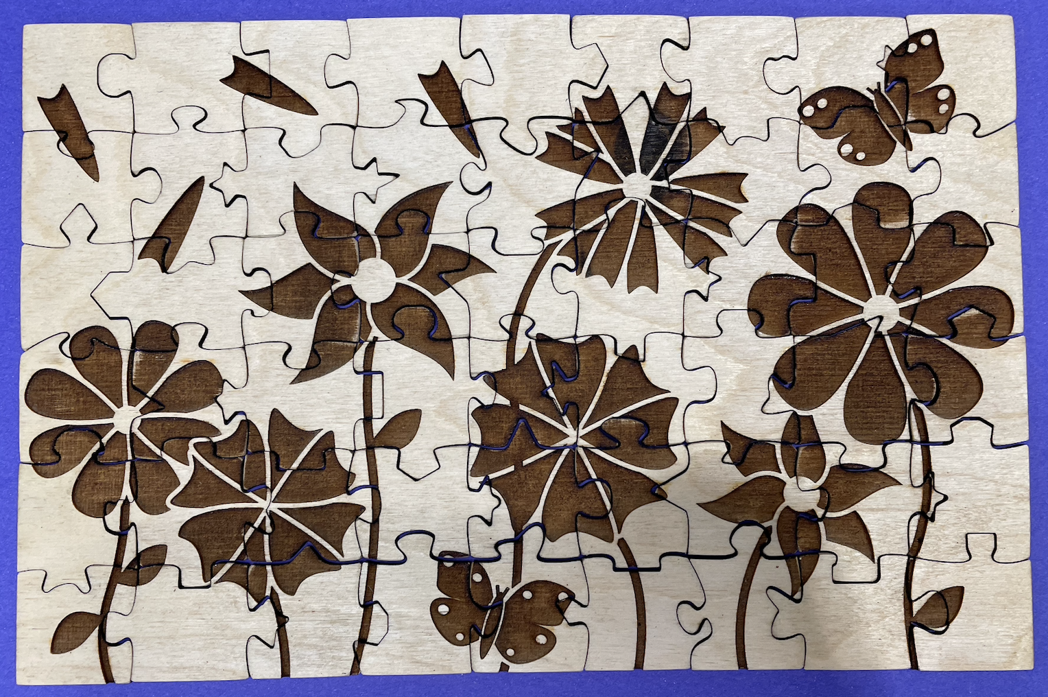 Top view of puzzle with all the pieces put together. The puzzle is tan with dark brown etching and is sitting on a bright purple background.