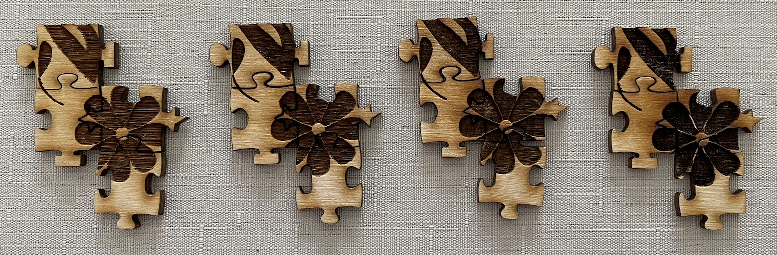 Four sets of four tactile puzzle pieces. Each set has the same piece but with different tactile depth. The pieces form a zigzag pattern, with one piece being an edge piece and the other three not.